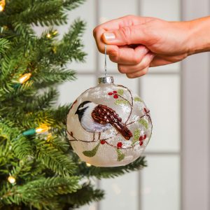 Hand placing LED Christmas Ornament on Christmas Tree.