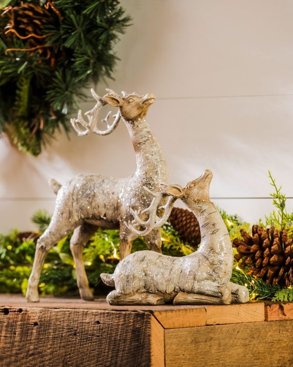 Decorate for winter with this décor. The reindeer look like they are carved from white birch bark and dusted with glitter. One is lying down and the other is standing, but both have their heads tilted up. They are made of polystone.  Buy now online or visit our Christmas Store.  Elkin Lawn and Garden in the heart of the Yadkin Valley.